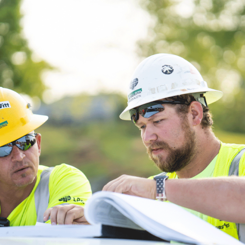 Two LPC workers look through their site plans while on a job in Kentuckiana.