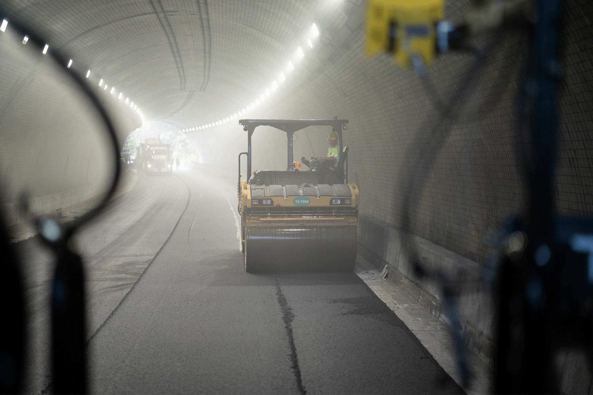 An asphalt roller rolls over fresh asphalt in a tunnel in Kentuckiana
