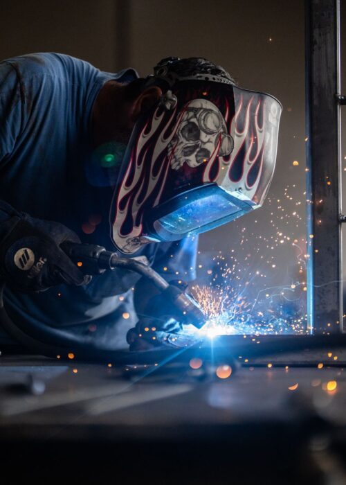 An Louisville Paving & Construction worker welds with PPE