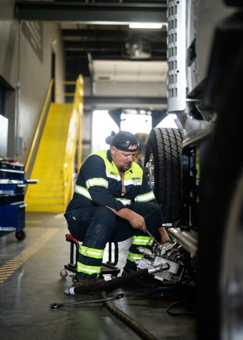 An LPC employee maintains a truck by checking the tires