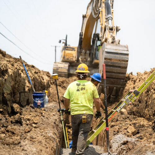 An LPC worker stands inside a trench underneath a crane in Kentuckiana