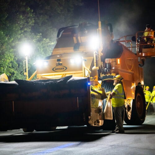A bulldozer sits with lights on in a dark street on a night time construction site for LPC in Kentuckiana