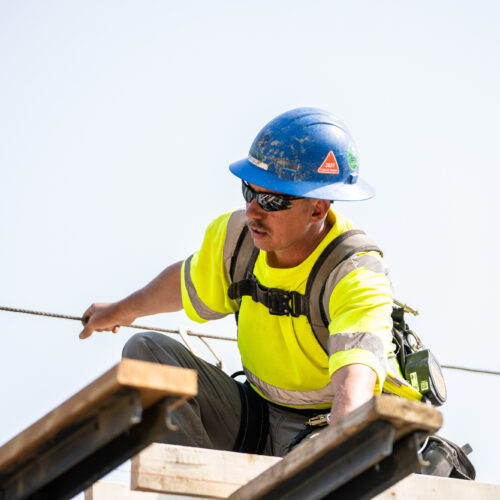 An LPC construction worker balances on a piece of heavy civil equipment in Kentuckiana