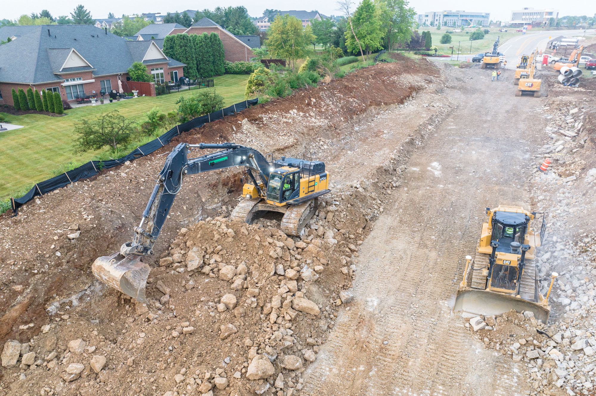An aerial view of a crane digging into dirt on a site in Kentuckiana